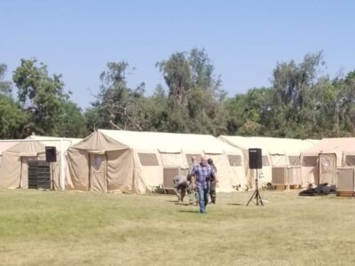 medical tents in a field with people walking toward camera