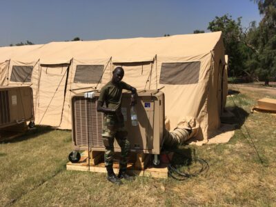 person leans on equipment in front of tent