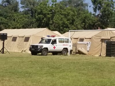 medical tents in a field with a white ambulance